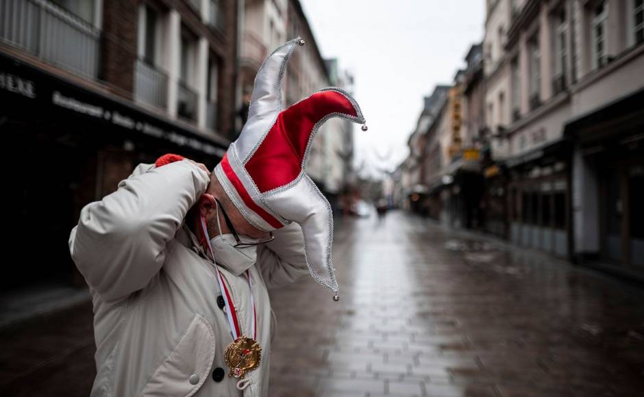 A man wearing a carnival cap stands in a deserted street in the old town in Duesseldorf, Germany, Monday. Because of the coronavirus pandemic the traditional carnival parades are canceled. Fabian Strauch/DPA via AP A man wearing a carnival cap stands in a deserted street in the old town in Duesseldorf, Germany, Monday. Because of the coronavirus pandemic the traditional carnival parades are canceled. Fabian Strauch/DPA via AP