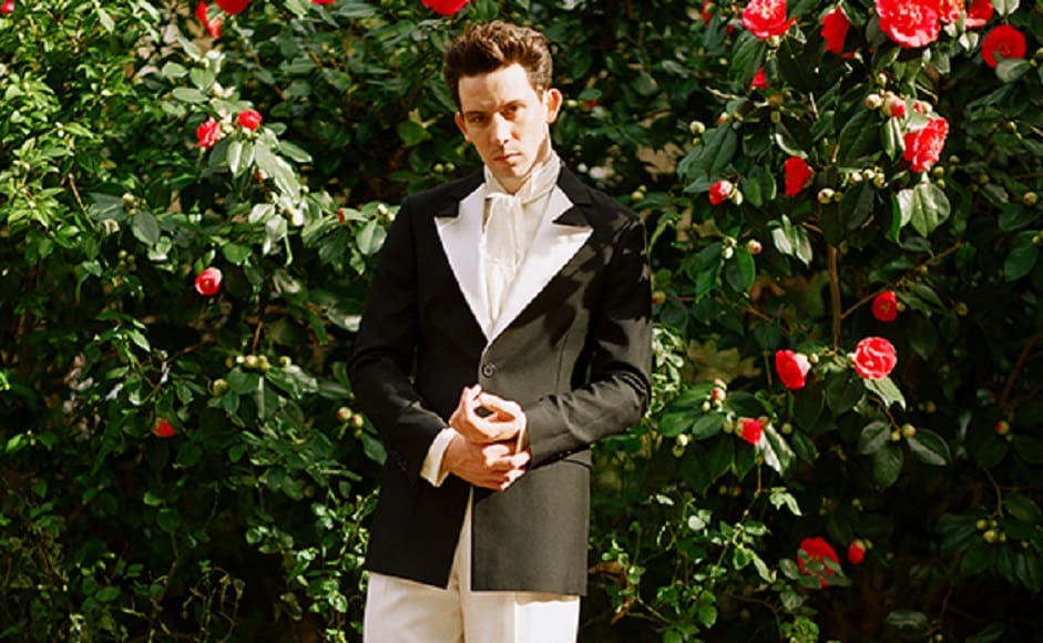 Josh O’Connor posed in front of roses in a black-and-white contrasting LOEWE suit| Image - William Waterworth