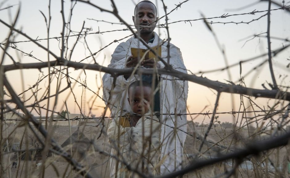 An Orthodox Christian refugee who fled the conflict in Ethiopia's Tigray region reads prayers with his son in front of a church at the Hamdeyat Transition Center near the Sudan-Ethiopia border, eastern Sudan, on Tuesday, 16 March, 2021. Political tensions between Ethiopian Prime Minister Abiy Ahmed's government and the Tigray leaders who once dominated the country's government exploded in November into war. Photo by The Associated Press/Nariman El-Mofty An Orthodox Christian refugee who fled the conflict in Ethiopia's Tigray region reads prayers with his son in front of a church at the Hamdeyat Transition Center near the Sudan-Ethiopia border, eastern Sudan, on Tuesday, 16 March, 2021. Political tensions between Ethiopian Prime Minister Abiy Ahmed's government and the Tigray leaders who once dominated the country's government exploded in November into war. Photo by The Associated Press/Nariman El-Mofty