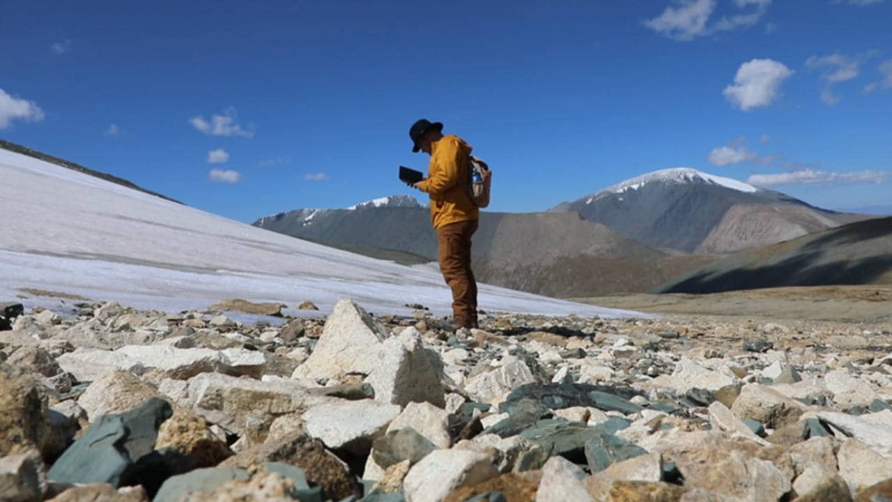 Archaeologist and paleoenvironmental researcher Isaac Hart of the University of Utah surveys a melting ice patch in western Mongolia. Peter Bittner, CC BY-ND