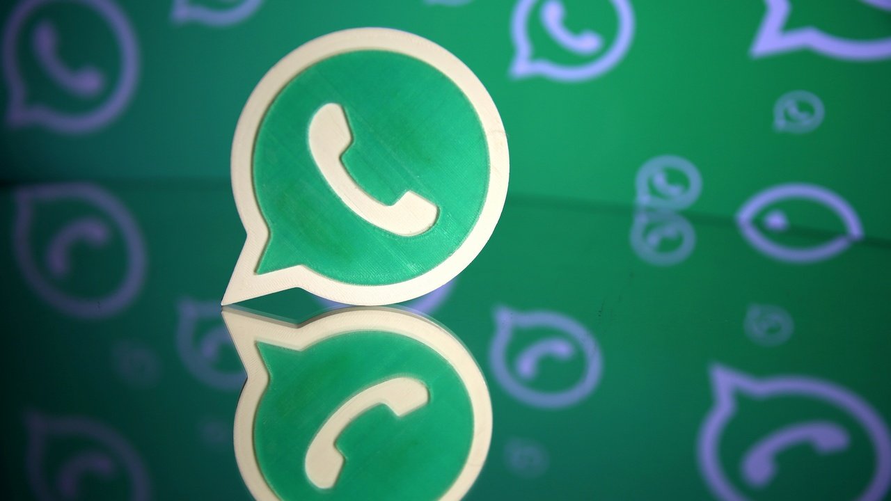 A 3D printed Whatsapp logo is seen in front of a displayed Whatsapp logo in this illustration