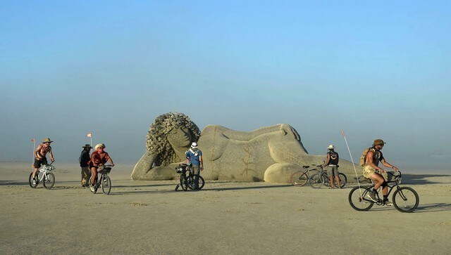 Participants ride their bikes as they pass through an art piece at the Burning Man Festival. The name ‘Burning Man’ comes from the symbolic ritual of burning a large wooden sculpture, the Man. AP Participants ride their bikes as they pass through an art piece at the Burning Man Festival. The name ‘Burning Man’ comes from the symbolic ritual of burning a large wooden sculpture, the Man. AP