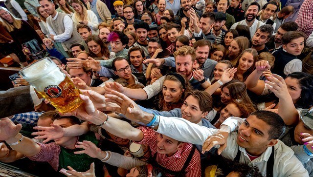 Youngsters reach out for beer at the Oktoberfest. The beer festival generates about 1.2 billion euros in income, according to a report by France24. AP Youngsters reach out for beer at the Oktoberfest. The beer festival generates about 1.2 billion euros in income, according to a report by France24. AP