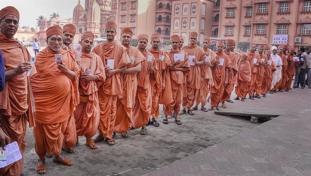 Saints from Swaminarayan show their ID cards as they wait in line to cast their vote in Surat. PTI Saints from Swaminarayan show their ID cards as they wait in line to cast their vote in Surat. PTI