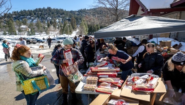 Community members also have been helping each other through the Rim Guardian Angels Facebook group. In this picture, Crestline residents can be seen receiving free food at a tent set up in front of the Goodwin & Son’s Market in Crestline, California. AP Community members also have been helping each other through the Rim Guardian Angels Facebook group. In this picture, Crestline residents can be seen receiving free food at a tent set up in front of the Goodwin & Son’s Market in Crestline, California. AP