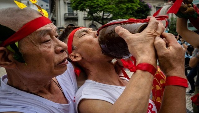 A performer gives rice wine to another to drink during the Drunken Dragon celebration. The players act while holding a spirits jar and spraying alcohol over the wooden dragon after taking a sip. AFP A performer gives rice wine to another to drink during the Drunken Dragon celebration. The players act while holding a spirits jar and spraying alcohol over the wooden dragon after taking a sip. AFP