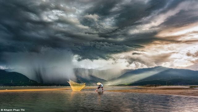 In the Storm: Lap An Lagoon in Hue province in the dry season. When the water recedes, the fish are stuck in puddles and when the tide is low, people often go fishing here. When I arrived at Lap An Lagoon, the storm came. The people were very afraid of lightning, but I stayed to witness the change of the storm when Heaven and Earth seemed to be connected by wind and water. Image Courtesy: Khanh Phan Thi/Pink Lady® Food Photographer of the Year 2023