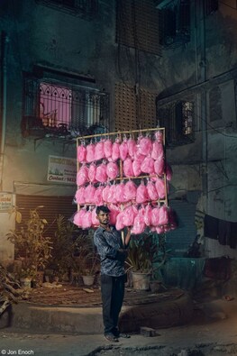The Candy Man: Pappu Jaiswal – a candyfloss seller in Mumbai, India holds his display of brightly coloured confectionery on the streets near to Versova Beach. Never more popular than in the age of social media for some eye-catching likes, the pink sugar clouds are popular for those looking for an affordable treat. Image Courtesy: Jon Enoch/Pink Lady® Food Photographer of the Year 2023