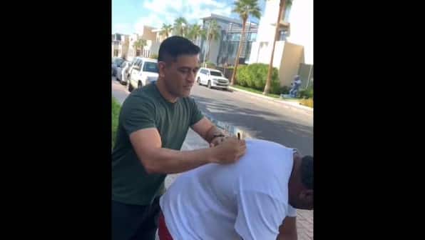 Fan bends over for MS Dhoni to sign his white t-shirt