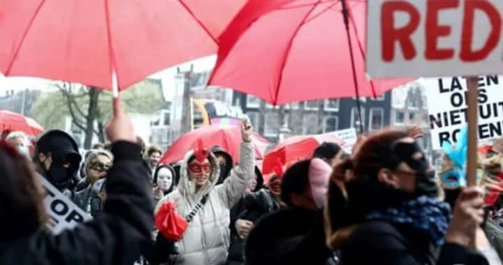 What is the controversy over Amsterdam mayor's plan to move legal prostitution from city's historic red light district?