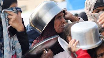 Displaced Palestinians wait to receive free food at a tent camp, amid food shortages, in Rafah. Reuters