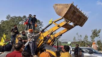 Farmers near a backhoe loader modified to shield from police rubber bullets at the Punjab-Haryana Shambhu Border, in Patiala district, as they gear up to resume their Delhi Chalo march. PTI
