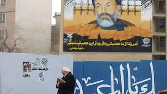 An Iranian man walks past campaign posters for the parliamentary election in Tehran, Iran. Reuters