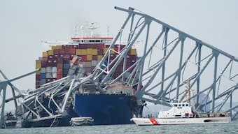 A Coast Guard cutter passes a cargo ship that is stuck under the part of the structure of the Francis Scott Key Bridge after the ship hit the bridge in Baltimore, Md. AP