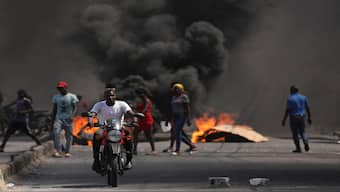 A man drives past a burning barricade during a protest against Prime Minister Ariel Henry's government and insecurity, in Port-au-Prince, Haiti. Reuters File