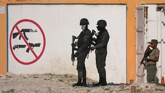 Soldiers stand guard next to a sign prohibiting the use of weapons outside the military headquarters as Haiti continues in a state of emergency, in Port-au-Prince, Haiti on 6 March, 2024. Reuters