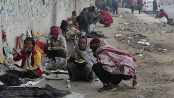 Homeless people, living under a flyover, have their meal in New Delhi. PTI