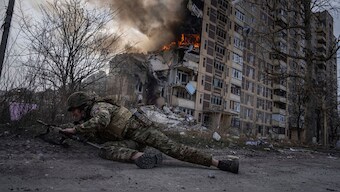 (File) A Ukrainian police officer takes cover in front of a burning building in Avdiivka, Ukraine, on 17 March, 2023. AP