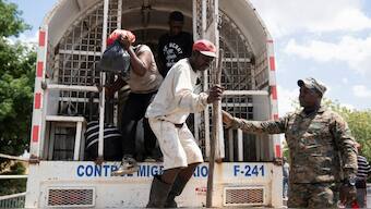 A member of the Dominican Republic security forces stand guard as Haitian citizens get off a truck to be deported on the border between Haiti and Dominican Republic, as gang violence continues. Reuters 