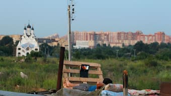 A migrant worker watches a film on his laptop on top of a shelter outside Moscow. Reuters file