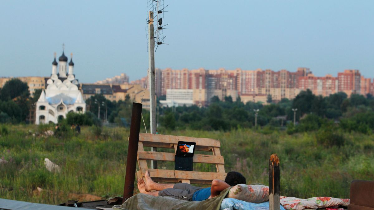 A migrant worker watches a film on his laptop on top of a shelter outside Moscow. Reuters file A migrant worker watches a film on his laptop on top of a shelter outside Moscow. Reuters file