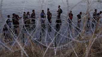 Migrants wait to climb over concertina wire after they crossed the Rio Grande and entered the US from Mexico, in Eagle Pass, Texas. A federal appeals court issued an order that prevents Texas from arresting migrants suspected of entering the US illegally, hours after the supreme court allowed the strict new immigration law to take effect. File photo/AP
