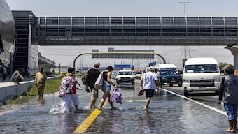 People walk through floodwater caused by heavy rain while waiting for transportation on Sheikh Zayed Road highway in Dubai, United Arab Emirates. Dubai recorded its heaviest rains in 75 years on 15 April. AP