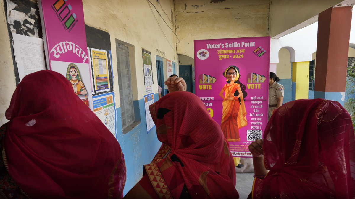 Women wait to cast their votes as one of them stands behind a selfie point during the first round of voting of India's national election in Behror, Rajasthan, on 19 April 2024. AP Women wait to cast their votes as one of them stands behind a selfie point during the first round of voting of India's national election in Behror, Rajasthan, on 19 April 2024. AP
