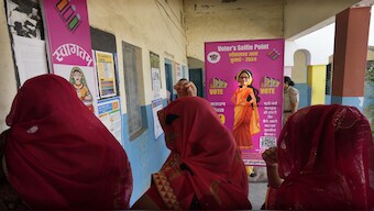 Women wait to cast their votes as one of them stands behind a selfie point during the first round of voting of India's national election in Behror, Rajasthan, on 19 April 2024. AP
