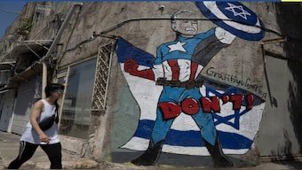 A person walks past a mural depicting the US president Joe Biden as a superhero defending Israel on a street in Tel Aviv, Israel. AP