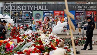 A police officer stands guard next to a makeshift memorial near the Crocus City Hall following a deadly attack on the concert venue outside Moscow on 26 March, 2024. Reuters