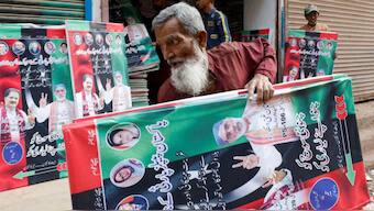 A worker carries campaign posters of a political party to decorate the area, ahead of general elections, in Karachi, Pakistan January 23, 2024. REUTERS. 
