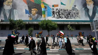 Iranian worshippers walk past a mural showing the late revolutionary founder Ayatollah Khomeini, right, Supreme Leader Ayatollah Ali Khamenei, left, and Basij paramilitary force, in an anti-Israeli gathering after their Friday prayer in Tehran, on 19 April 2024. AP