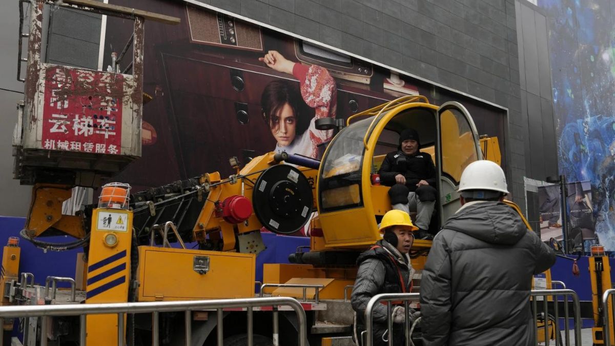 Men work with a crane near an advertisement at a shopping mall in Beijing. Source: AP / File Photo Men work with a crane near an advertisement at a shopping mall in Beijing. Source: AP / File Photo