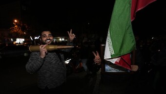 Iranian demonstrators flash the victory sign as they hold an Iranian flag and a model of a bullet during an anti-Israeli gathering at the Felestin (Palestine) Square in Tehran, Iran, early Sunday. Iran launched its first direct military attack against Israel on Saturday. AP
