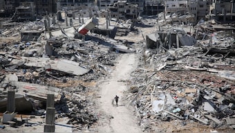 A man pushes a bycicle along as he walks amid building rubble in the devastated area in Gaza, amid the ongoing conflict between Israel and the Palestinian Hamas militant group. AFP