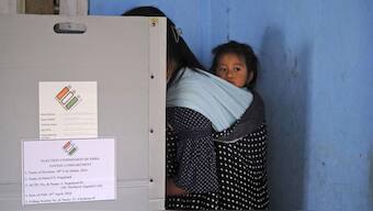 A child looks on from a sling on the back of her mother as she casts her vote during the first round of polling of the Lok Sabha election in Chedema village, in Nagaland, Friday. AP
