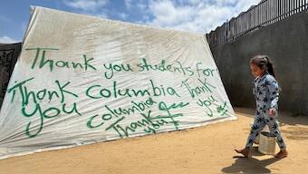 A girl walks next to a tent sprayed with a message in solidarity with pro-Palestinian university students, amid the ongoing conflict between Israel and Palestinians, in Rafah in the southern Gaza Strip, May 2, 2024. Image: REUTERS