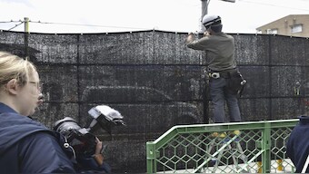 A worker sets up a huge black screen on a stretch of sidewalk at Fujikawaguchiko town, Yamanashi prefecture, central Japan. AP