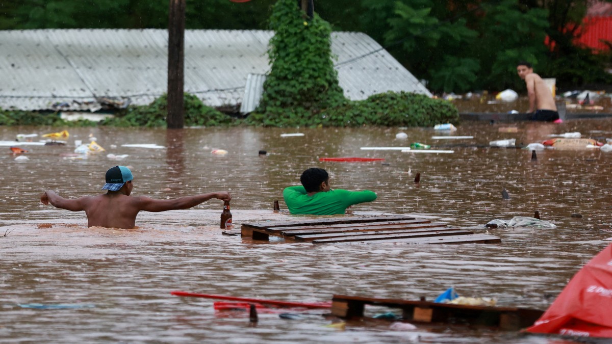People walk in a flooded area next to the Taquari River during heavy rains in Encantado, Rio Grande do Sul state, Brazil. Reuters People walk in a flooded area next to the Taquari River during heavy rains in Encantado, Rio Grande do Sul state, Brazil. Reuters