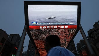 A person looks at a screen showing news footage of military drills conducted in areas around the island of Taiwan by the Eastern Theatre Command of the Chinese People's Liberation Army (PLA), in Beijing, China. Reuters