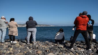 People watch surfers taking part in a ceremony in honor of two Australians and an American surfers that went missing last week during a surfing trip at San Miguel Beach in Ensenada, Baja California State, Mexico. AFP