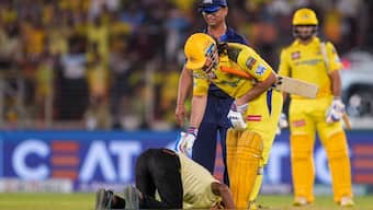 The fan who invaded the pitch during GT vs CSK IPL 2024 clash in Ahmedabad touches MS Dhoni's feet. Image: PTI 