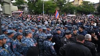 Armenian law enforcement officers stand guard outside Prime Minister Nikol Pashinyan's residence as demonstrators gather near it to demand his resignation over land transfer to neighbouring Azerbaijan, in Yerevan on May 26, 2024. 