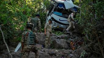 Security men inspect a bus that fell into a deep gorge on Sunday after it was fired at by suspected militants in Reasi district, Jammu and Kashmir, on 10 June 2024. AP