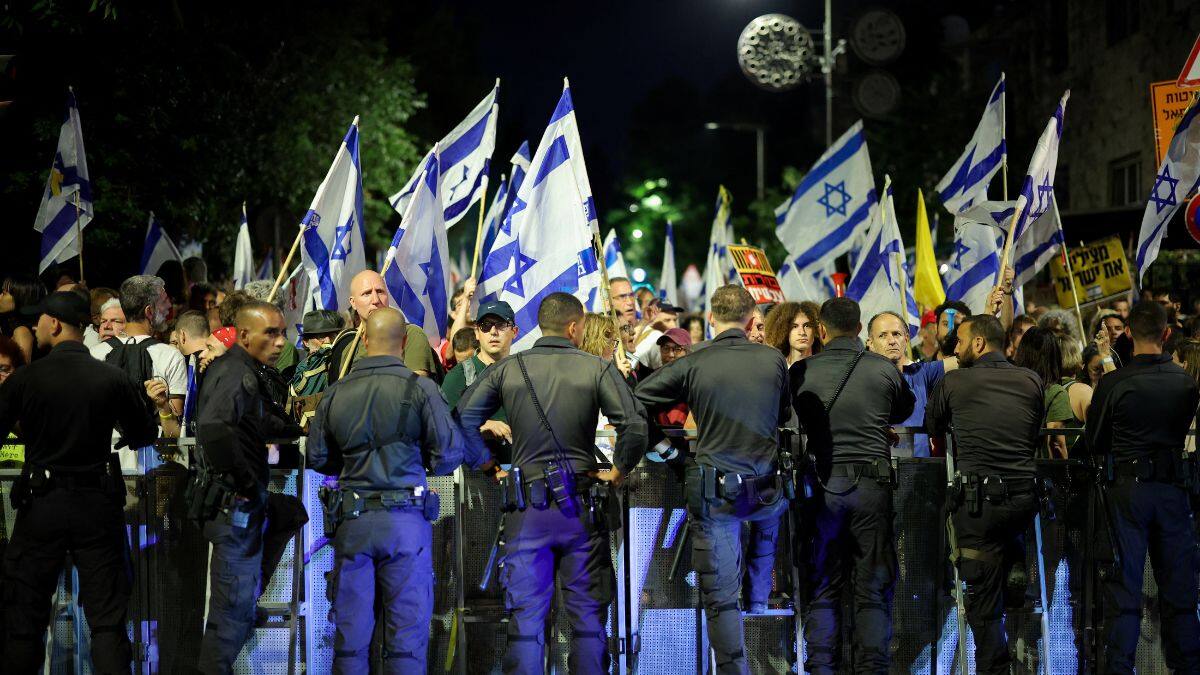 Members of Israeli security forces stand guard next to protesters during a demonstration against Israeli Prime Minister Benjamin Netanyahu's government, near the Knesset, the Israeli parliament, in Jerusalem, 17 June, 2024. Reuters