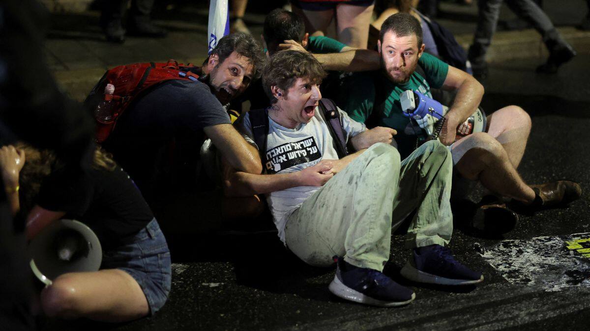 Demonstrators sit while holding each other's arms during a demonstration against Israeli Prime Minister Benjamin Netanyahu's government, near the Knesset, the Israeli parliament, in Jerusalem, 17 June, 2024. Reuters
