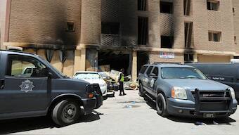 A Kuwaiti police officer is seen in front of a burnt building following a deadly fire, in Mangaf, southern Kuwait. According to officials, of the 49 killed in the blaze, 42 were Indians. Reuters