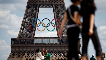 People walk at the Trocadero square as the Olympic rings are displayed on the Eiffel Tower, ahead of the Paris 2024 Olympic and Paralympic Games in Paris, France. Fears of a lingering heatwave have prompted teams to bring their own air conditioning to the City of Love for the Games. Reuters