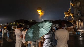 People watch the Olympic cauldron hover near the statue of Joan of Arc in Paris. AP